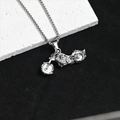 Détail du pendentif moto vintage avec roue en flammes sur une chaîne argent - Moto en argent