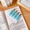 Set of 4 light blue seamless hair clips with a matte finish on a decorative book - Blue