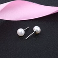 Macro-opname van natuurlijke zoetwaterparel oorbellen op zwart zand met roze lint detail - 4-5mm / Wit
