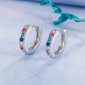 Silver huggie hoop earrings with multi-colored crystals on light blue textured background - Platinum Tone with Multicolored Zirconia