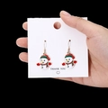 Festive Christmas snowman earrings with red scarf and green hat on white card - Christmas Snowman Enamel