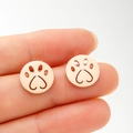 Close-up of rose gold hollow cat paw earrings with heart shaped pads held in hand - Rose Gold