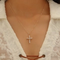 Close-up of a gold cross necklace with clear zircons worn by a model in white lace - Pave Rhinestone Cross Style (9556) / KC Gold