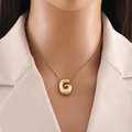 Dettaglio della modella che indossa un ciondolo con lettera G placcato oro 18K su catena - Lettera G