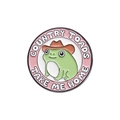 Pink round enamel pin with a cowboy frog and Country Toads Take Me Home text - Cowboy Frog