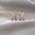 Detail of gold X-shaped earrings with pearls and crystals on champagne silk background - X-Shape Cross Pearl Zirconia Post Style (A15)