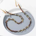 Macro detail van een barnsteenkleurige acryl brillenketting met gouden metalen schakels - koffiekleur