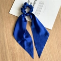 Detail van een marineblauwe satijnen haarelastiek met lange linten op bureau - Koningsblauw Satijnen Lint