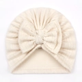 Detailed view of cream textured knit baby turban hat featuring a large soft front bow - One Size / Beige