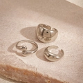 Vista detallada de tres anillos metálicos minimalistas plateados sobre una piedra rosada - Gota de Agua Plateada (Juego de 3)