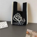Knitted rose pattern tote bag in black and white with striped edges on a desk - Black
