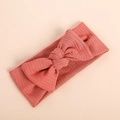 Detail of coral ribbed knit infant headband featuring a soft textured bow design - Orange Red