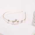 Elegante diadema de metal dorado con estrellas de strass brillantes en soporte blanco - Estrella de Cinco Puntas Dorado