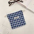 Detail eines blau karierten Strickbeutels mit Kordelzug und Webetikett auf weißem Grund - Beschichtetes blaues Karo