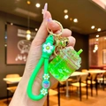 Close-up of a green liquid quicksand cup keychain with strawberry silicone strap and golden bell - Strawberry Strap Green Luminous Dried Flower Iceberg Cup