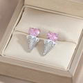 Detailed close-up of pink heart zircon ice cream stud earrings in a beige jewelry box - Silver