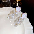 Detailed close-up of acrylic flower tassel earrings with pearlescent finish on a ceramic plate - Silver Pin - White Flower Drop Earrings