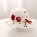 Close-up of baby sun hat featuring red bow prints and delicate white lace edges - 48cm (5-18 Months) / Off-white with Red Bow Print
