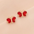 Elegant gold butterfly earrings featuring vibrant red faceted zircon stones on fabric - Red