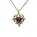 Collana dorata con pendente a cuore in cristallo blu e cornice in filigrana su sfondo bianco - Blu