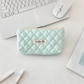 Close-up of mint green quilted makeup bag with dog label on a minimalist white desk - Mint Green
