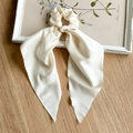 Close-up of elegant ivory satin scrunchie with long streamers on a wooden background - Milky White