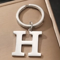 Polished silver metal keychain with uppercase letter H on a textured brown surface - Letter H