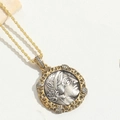 Dettaglio del ciondolo a moneta faraone vintage con rilievo argento e bordo oro - Stile Zircone Bianco
