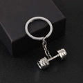 Sleek silver dumbbell keychain made of polished metal on a textured black surface - Dumbbell Style-D1331-1 / Silver