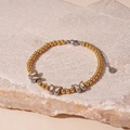 Macro detail van de vlinderbedels en gouden kralen op een vintage armband - Gouden Kralen Vlinder Stijl