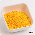 Macro shot of 3mm bright yellow round glass seed beads in a white square container - KK09 Orange Yellow