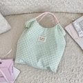Macro shot of green plaid canvas tote bag with pink woven rope handle and brand logo - Wrinkled Green Plaid