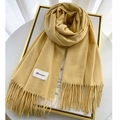 Detalle de bufanda de cachemira amarilla con flecos finos y etiqueta de marca tejida - Amarillo Oca