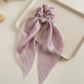 Detail of lavender nylon hair scrunchie with long ribbons on a beige ceramic plate - Purple