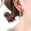 Vintage style gold earrings with green pavé crystals shown on a model's ear - Gold Green Zirconia