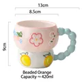 Pink and white ceramic mug with relief orange patterns and a blue beaded handle - Beaded Orange