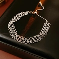 Detail of silver lace cutout woven bracelet on textured black leather backdrop - Silver (Real Gold Plated)