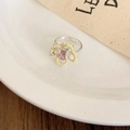 Primer plano de anillo de flor amarilla con gema rosa y pedrería en plato de cerámica - Juego de tres piezas en plata amarillo y azul - Forma de flor(HR2680)