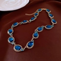 Dettaglio di collana vintage con gemme ovali blu scuro e metallo bronzo su tessuto - Collana / Oro/Blu Scuro