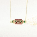 Detail of gold evil eye necklace pendant with red green enamel and inscribed WILL text - WILL/Evil Eye/Red Green White