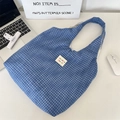 Detailed top view of blue checkered cotton tote bag with brand label on office desk - Blue Plaid