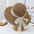 Detailed view of brown straw hat featuring white lace bow and elegant wavy brim - One Size / Khaki