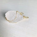 Natural raw rose quartz pendant wrapped in 18K gold wire on a wooden surface - Gold Wire Clear Quartz