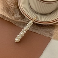 Detailed macro view of elegant faux pearl gold hair clip on a vintage leather surface - Four Flowers-Gold Hair Clip