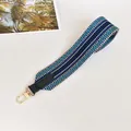 Close-up of blue and green striped woven strap with green leather and gold metal clips - Blue with Green Trim
