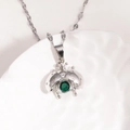 Détail d'une chaîne en titane argentée avec pendentif coccinelle et pierre verte - Platine Zirconia Vert