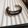 Macro detail of irregular wave resin bangle featuring black and gray marble smoke patterns - Black Smoke