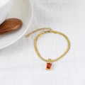 Bracciale dorato con un pendente rettangolare rosso su sfondo in tessuto bianco - Bracciale / Rosso