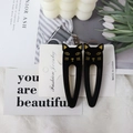 Pair of black acetate cat hair clips with gold details on a fashion jewelry card - Black