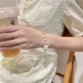 Elegant gold pearl bracelet with white rose charm shown on model wrist for a sweet look - Camellia White